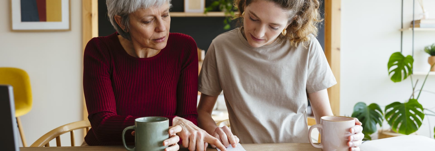 Dwie kobiety analizujące paragony i rachunki przy stole z kawą