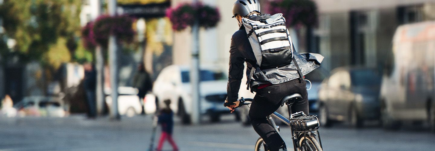 Mężczyzna w kasku porusza się na rowerze po mieście