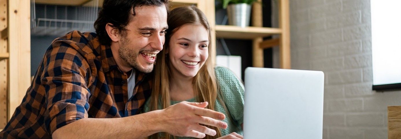 Ojciec z córką oglądają coś wspólnie na laptopie.
