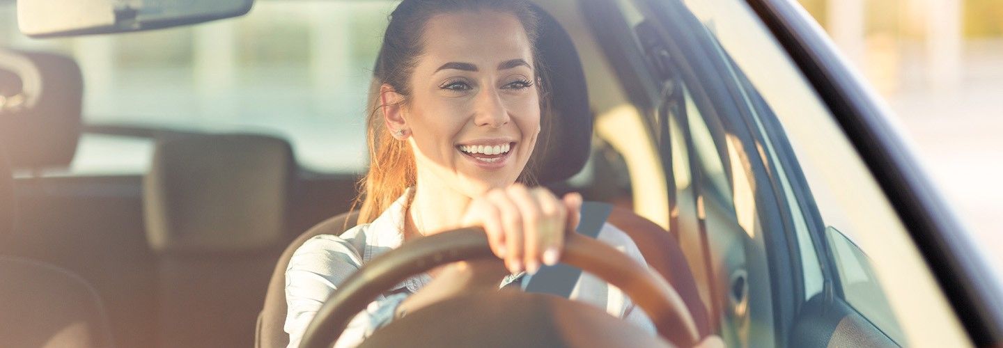 Uśmiechnięta kobieta za kierownicą samochodu