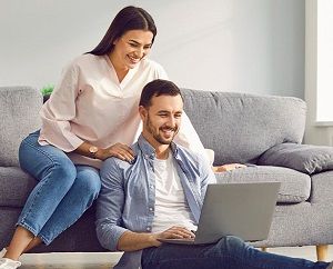 Usmiechnieta para wspolnie spedza czas w salonie ogladajac cos na laptopie