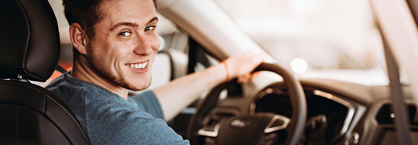 Zadowolony mężczyzna siedzi za kierownicą swojego samochodu