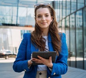 kobieta z tabletem stoi przed biurem.