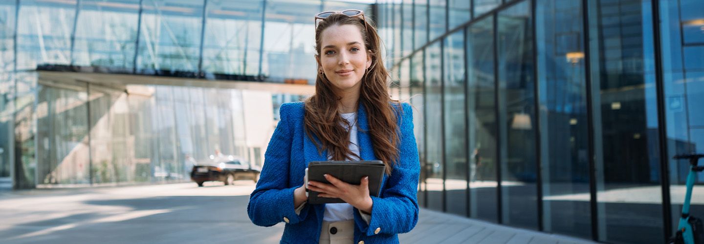 Kobieta z tabletem stoi przed biurem.