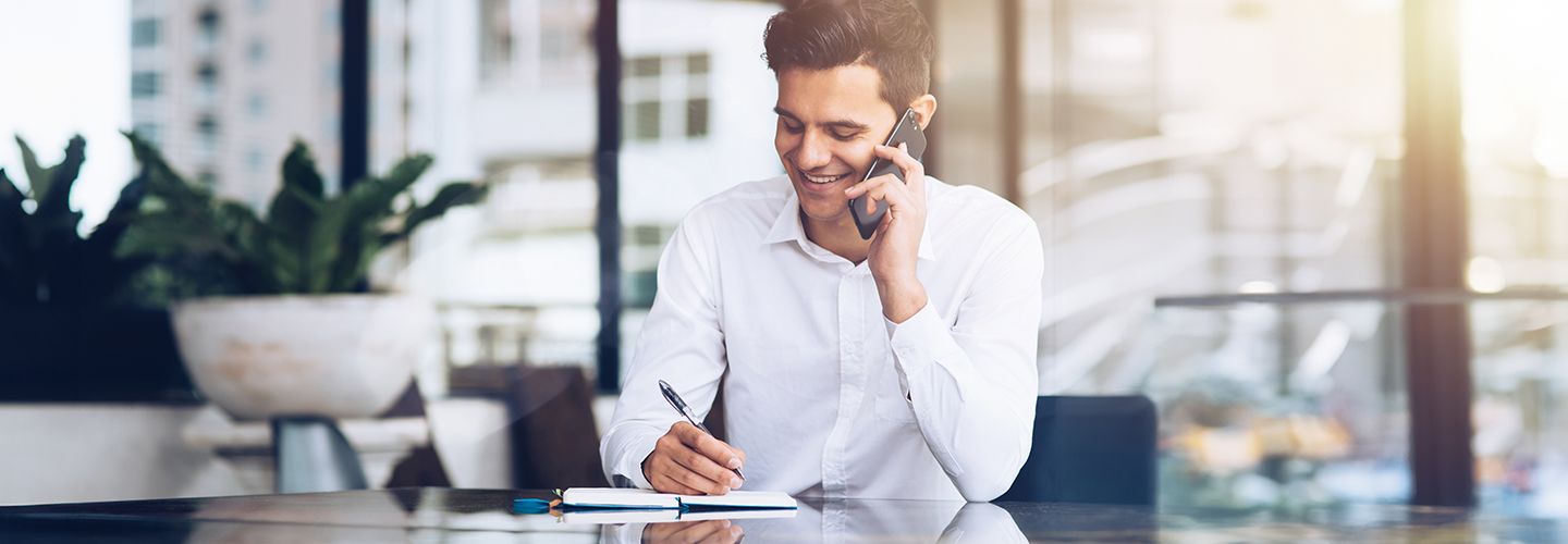 Mężczyzna rozmawia przez telefon i zapisuje coś w notatniku.