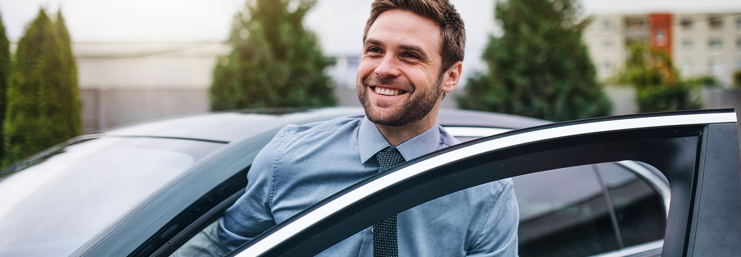 uśmiechnięty mężczyzna wysiada z samochodu.