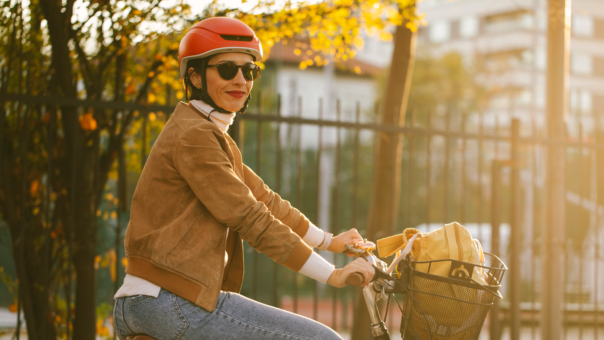 Kobieta jedzie na rowerze jesienią po parku, ciesząc się kolorowymi liśćmi i chłodnym powietrzem